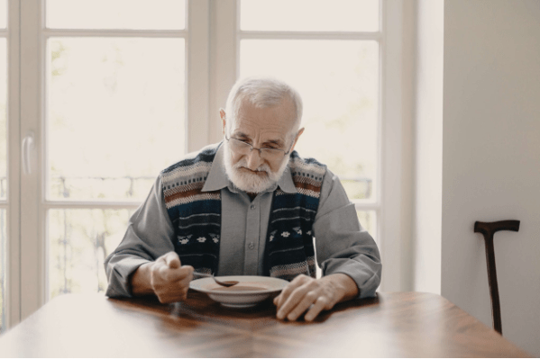 An older man eating soup