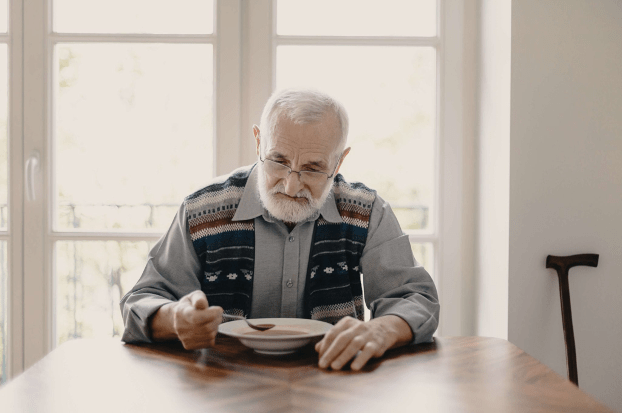 An older man eating soup